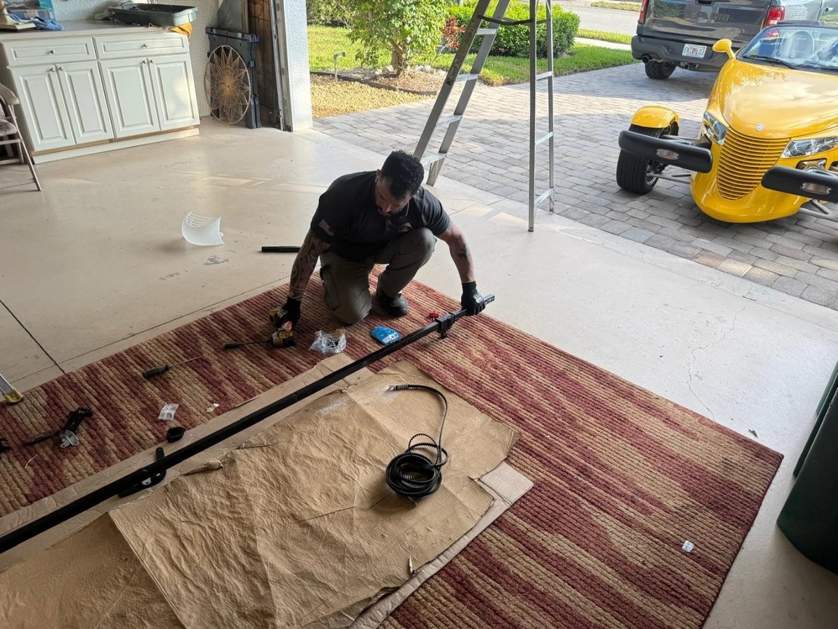 Technician kneeling on a rug beside a long black shaft and a coil of cable