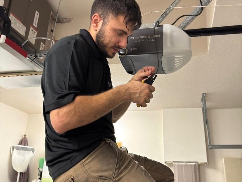 Technician using a screwdriver beside an opener motor unit