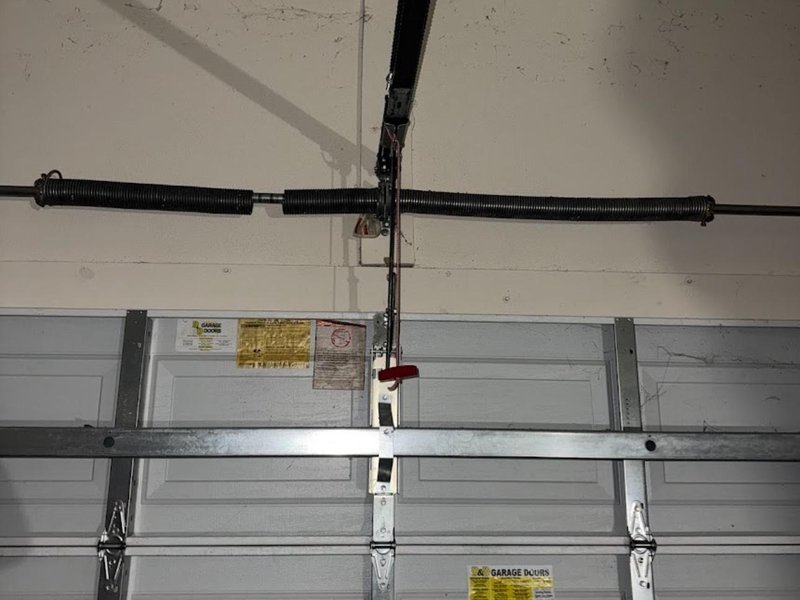 Torsion spring and bracket above the top panel of a garage door