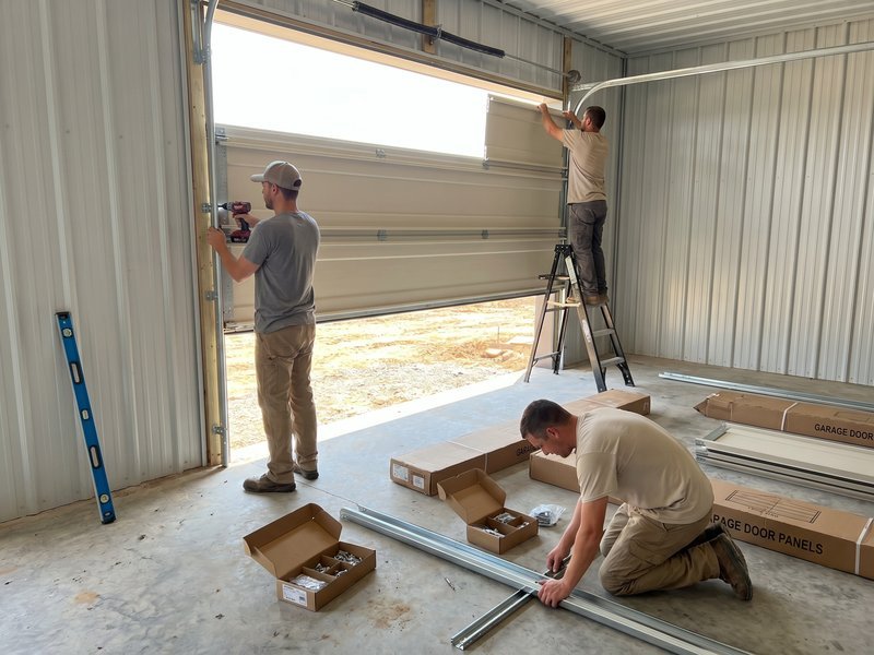 Two technicians with boxes of door sections laid out on a garage floor